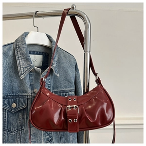 Detail of dark red pleated underarm bag with silver buckle and eyelet strap detail