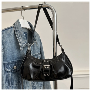 Detail of glossy black faux leather shoulder bag featuring silver metal eyelets and buckle