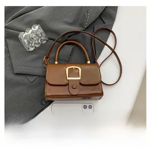 Dettaglio della piccola borsa a mano marrone con texture e fibbia in metallo e smartphone