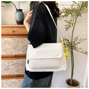 Détail du sac bandoulière en nylon blanc avec étiquette mode et pendentif jaune
