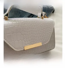 Gros plan sur le sac en cuir gaufré crocodile blanc avec boucle en métal doré chic