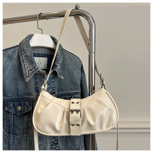 Detail of creamy white hobo bag featuring vintage pleats and metallic buckle strap