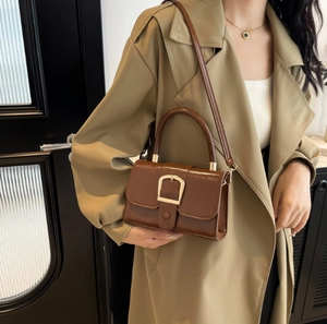 Dettaglio di una borsa vintage in pelle oliata marrone scuro con fibbia dorata a ferro