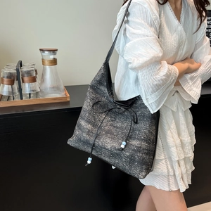 Denim tote bag with bow and bead charms shown on a model in a cafe setting