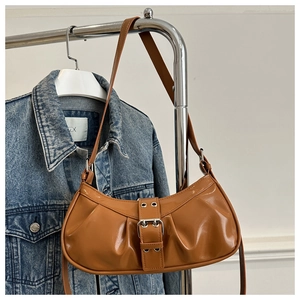 Close-up of vintage pleated caramel shoulder bag featuring a metallic buckle detail