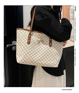 Gros plan du sac cabas beige avec motif monogramme marron et nœud doré élégant