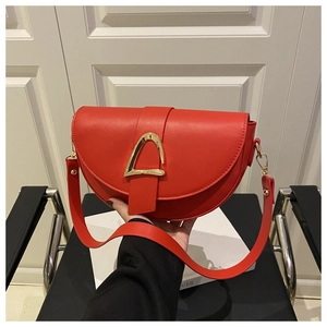 Close-up of red matte leather saddle bag with gold triangle buckle and wide strap
