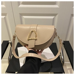 Detail of a beige saddle bag featuring a gold D-shaped buckle and premium leather texture