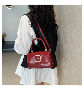 Vista posteriore di una modella con borsa in pelle rossa lucida e fibbia in oro