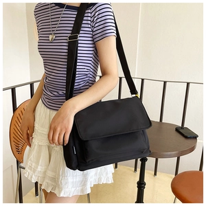 Détail d'un sac bandoulière en nylon noir avec étiquette mode et texture résistante