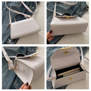 Détail de la texture crocodile et du fermoir doré sur un sac bandoulière blanc