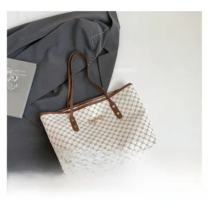 Gros plan du sac cabas beige avec motif monogramme vintage et détail de nœud en métal