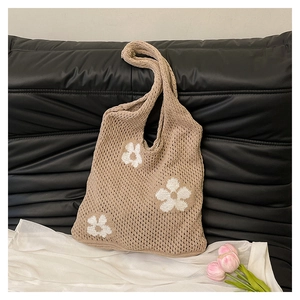 Close-up of knit tote bag with floral patterns and hollow crochet texture on sofa