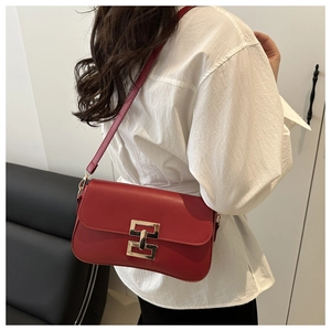 Detail view of red rectangular crossbody bag with golden H clasp on a model