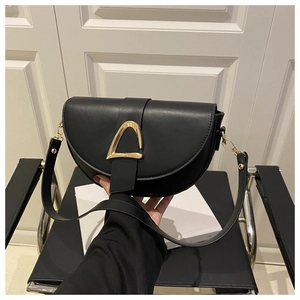 Detail of black half-moon shoulder bag with matte leather and gold triangle clasp