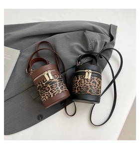 Detailed view of leopard print cylinder bags in black and brown on grey suit fabric