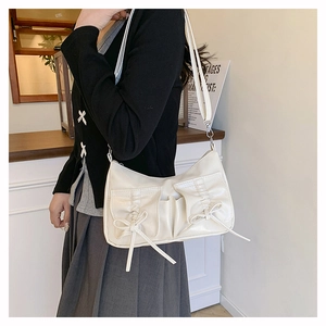 Détail du sac à bandoulière blanc avec nœuds et poches plissées porté par le mannequin
