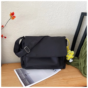 Détail de la sacoche en nylon noir sur une table en bois avec pendentif fleur jaune et boucle