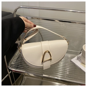 Detailed close-up of the vintage cream saddle bag featuring a signature gold triangle buckle