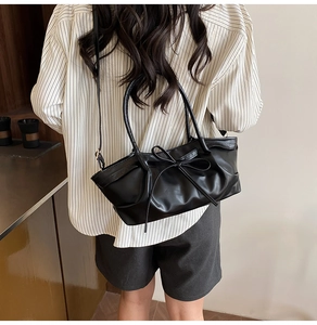 Détail du sac à main plissé noir avec nœud papillon et fine bandoulière réglable
