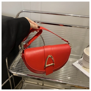 Detailed close-up of a red leather saddle bag featuring a gold horseshoe metal buckle clasp