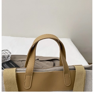 Detalle del bolso de lona con asas de cuero marrón y costuras en tela crema texturizada