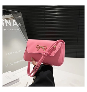 Detail of pink faux leather handbag featuring a stylish gold bow metal buckle and flap