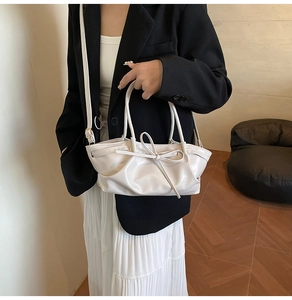 Close-up of cream bow-knot detail and pleated texture on a stylish leather tote bag