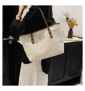 Vue latérale du cabas en toile beige avec motif monogramme marron et anses en cuir