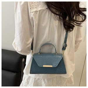 Vue arrière d'un mannequin portant un sac trapèze bleu effet croco avec boucle dorée