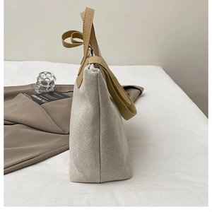 Vista lateral del bolso tote de lona grande con asas de cuero en contraste y diseño minimalista