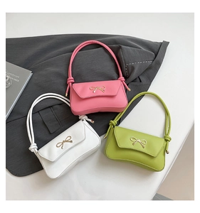 Detailed view of the elegant metal bow clasp on a smooth PU leather baguette bag