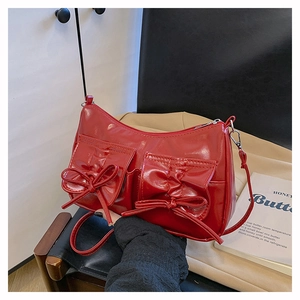 Détail d'un sac bandoulière rouge brillant avec deux grandes poches à nœuds décoratifs