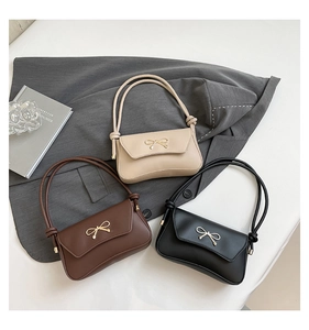 Close-up of three stylish bow-knot shoulder bags in off-white, coffee, and black tones