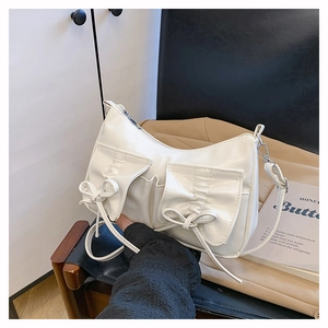 Détail du sac bandoulière blanc en similicuir avec nœuds et poches à rabat