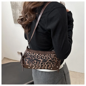 Detail view of leopard print shoulder bag with side bow accents on female model