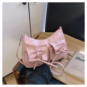 Détail du sac à main en cuir verni rose brillant avec nœuds et poches frontales