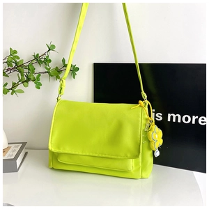 Detailansicht der neongelben Nylontasche mit Klappverschluss und süßem Blumenanhänger