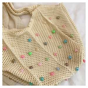 Detail of crochet cotton tote bag with colorful pearl beads and hollow mesh texture