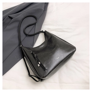 Detail view of black matte leather tote bag with vertical zipper and gold lettering