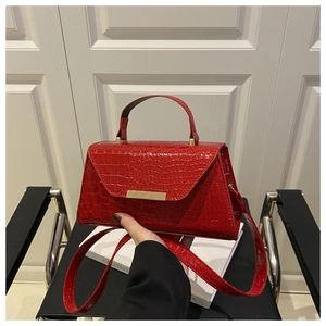 Vue détaillée du sac en cuir rouge motif crocodile avec fermoir métallique doré