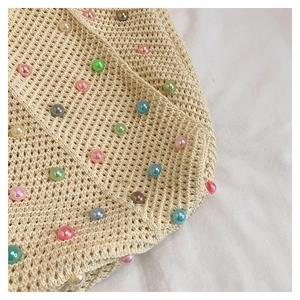 Close-up of beige knit tote bag featuring colorful faux pearls and crochet texture