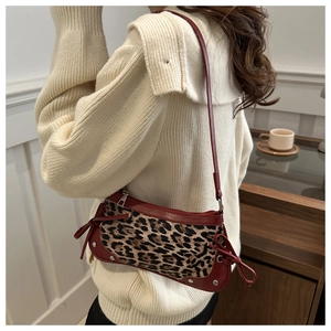 Detail view of leopard print canvas shoulder bag with red leather trim and side bow tie