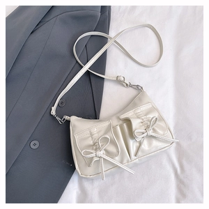 Detail of cream white PU leather crossbody bag featuring dual pockets and bow decorations