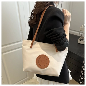 Fashionable beige tote bag with brown leather patch on a model for daily commuting