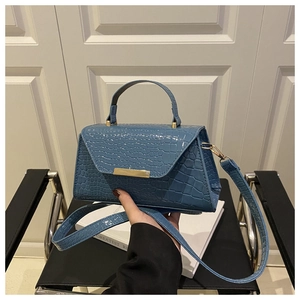 Détail du sac bleu motif crocodile avec boucle dorée élégante et poignée supérieure