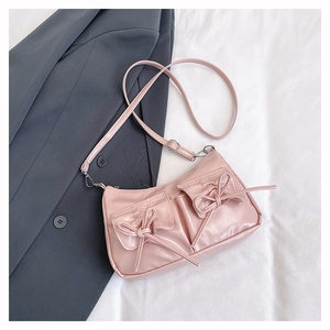 Detail of light pink crossbody bag with bow pockets on dark grey suit background