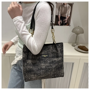 Detail of black glitter tote bag with gold chain strap and brand leather patch