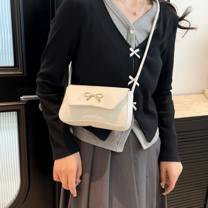 Chic beige shoulder bag with gold bow clasp shown on model for 2025 spring style