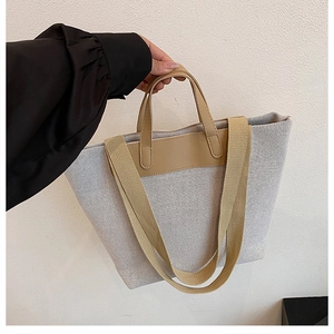 Detailed close-up of canvas texture and leather handles on casual beige tote bag